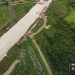 Drone view of a developing road corridor and surrounding land in Guyana, with the Invest Guyana Explains masthead.