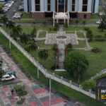 Aerial view of a Georgetown institutional property and surrounding commercial corridor, with the Invest Guyana Explains masthead.