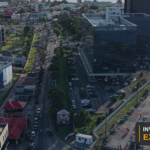 Drone view of Georgetown's commercial district and waterfront corridor, with the Invest Guyana Explains masthead.