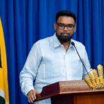 President Irfaan Ali speaking at a lectern during the September briefing, with the Guyana flag beside him.