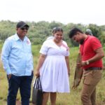 Housing Minister Collin Croal joins a family during a land-identification exercise