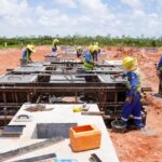 Workers in hard hats and high-visibility clothing working on substation foundations.