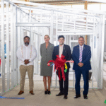 Officials at a ribbon-cutting inside a steel-frame structure at the US Frame Factory in Cove and John